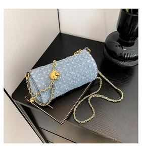 Détail d'un sac cylindre en denim bleu avec paillettes et bandoulière dorée