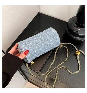 Détail du sac cylindre en jean bleu clair avec motif matelassé en losange et sequins argentés