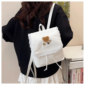 Detailed back view of a white nylon mini backpack with lace trim and plush bear patch