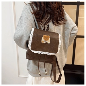 Détail du mini sac à dos marron vintage avec bordure en dentelle et écusson d'ours en PU