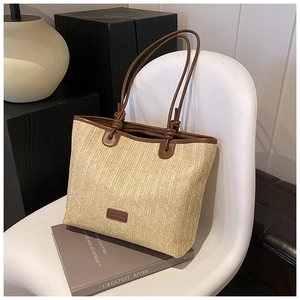 Detail of woven straw tote bag featuring brown leather straps and artisan knots
