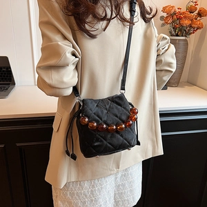 Sac seau matelassé noir avec perles d'ambre et bandoulière sur un mannequin