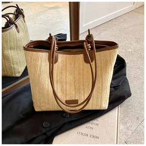 Detail of woven straw tote bag featuring brown leather handles and secure zip closure
