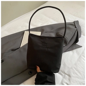 Detalle del bolso de tela negra con bordado de Hope and Future en la parte frontal