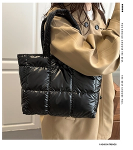Detail of black quilted down tote bag with waterproof nylon texture on shoulder