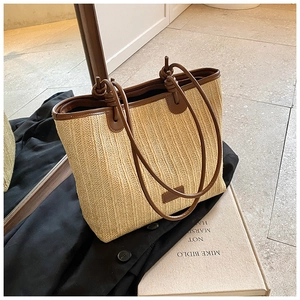 Detail of woven straw shoulder bag featuring brown leather trim and vertical texture
