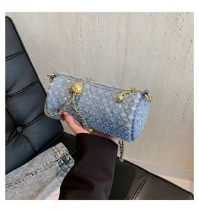 Détail du sac cylindre en jean bleu clair avec surpiqûres losanges et chaîne dorée