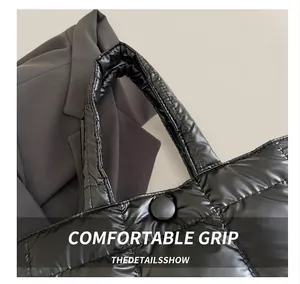 Detail of comfortable padded handles and snap closure on black quilted tote bag