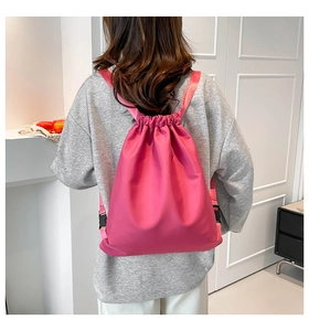 Detail view of pink nylon drawstring backpack showing adjustable straps and closure