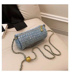 Détail du sac cylindre en jean bleu clair avec texture paillettes et chaîne dorée