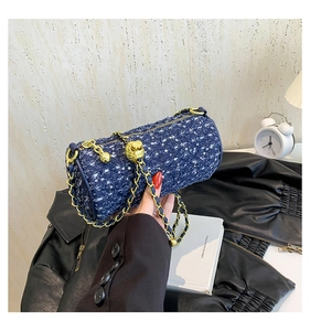 Vue détaillée du sac cylindre en tweed bleu foncé avec chaîne dorée et breloque en métal