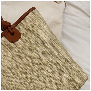 Close-up of woven straw texture and dark brown leather handle with knot details