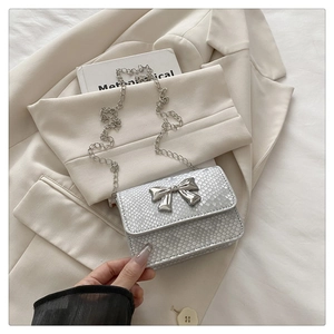 Close-up of silver snake embossed mini bag with metallic bow detail and chain strap