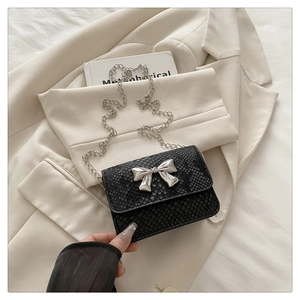 Close-up of black snakeskin patterned crossbody bag with a silver metallic bow and chain