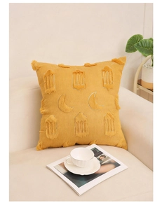 Détail de la housse de coussin en velours jaune avec broderie lune et finitions à pompons