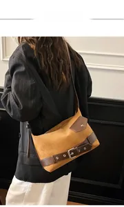 Detail of camel suede shoulder bag featuring a vintage brown leather buckle and pocket