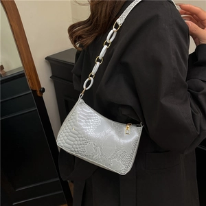 Grey snakeskin shoulder bag with unique ring chain strap worn as a chic underarm bag