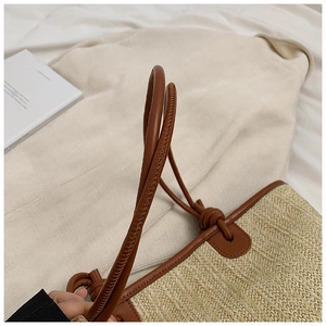Detail of hand-woven straw tote with premium brown leather handle and knotted buckle