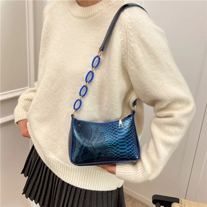 Blue snake skin shoulder bag with thick chain strap shown on model in a modern style