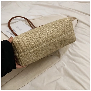 Detail shot of the sturdy woven base and side texture of a beige straw tote bag