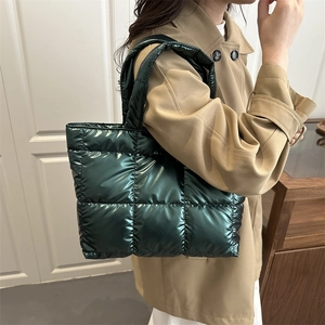 Deep green quilted puffer tote bag with glossy metallic finish for women in a city setting