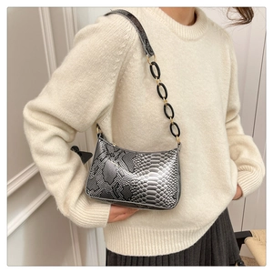 Silver snakeskin underarm bag with decorative metal chain shown on a shoulder