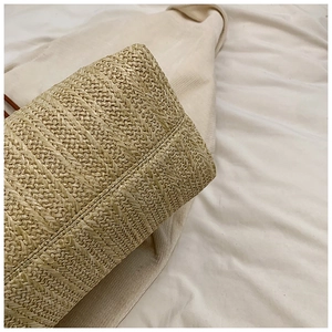 Close-up of intricate woven straw pattern and durable stitching on a beige shoulder bag