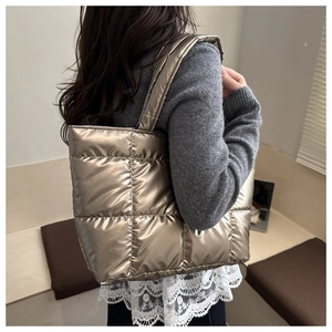 Close-up of champagne gold quilted tote bag with metallic finish on model's shoulder