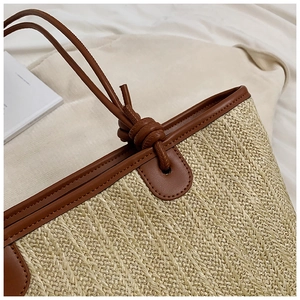 Close-up of woven straw tote bag featuring brown leather knot handles and refined texture