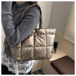 Detailed view of champagne gold quilted tote bag with soft padded texture and top handle