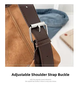 Detail of adjustable silver buckle and brown suede shoulder strap on a crossbody bag