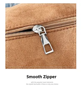 Detail of high-quality silver metal zipper on premium brown suede shoulder bag