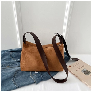 Detail of vintage brown suede shoulder bag on denim jacket featuring adjustable strap buckle