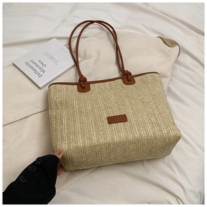 Detailed macro view of woven beige straw tote with brown leather straps and patch