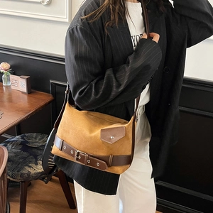 Caramel suede shoulder bag with brown leather buckle strap shown in a lifestyle setting