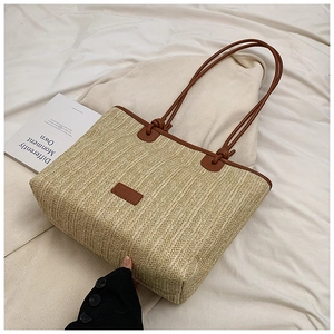 Close-up of woven straw tote bag with brown leather handles and textured stripe detail