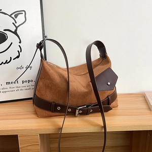 Detail of brown suede shoulder bag with decorative leather belt and side buckle pocket