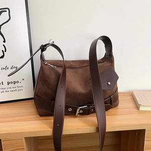 Detailed view of dark brown suede bag with retro leather straps and buckle decor