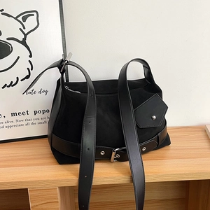 Detail of black suede tote bag with faux leather straps and silver metal buckles
