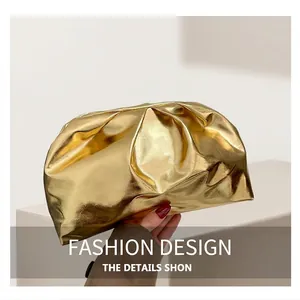 Detailed close-up of a gold metallic cloud clutch with luxury pleated texture on grey fabric