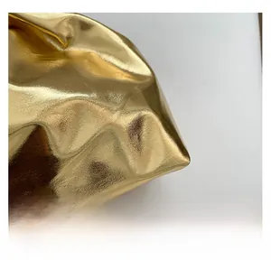Detailed close-up of metallic gold cloud bag showing luxury pleated texture and glossy finish