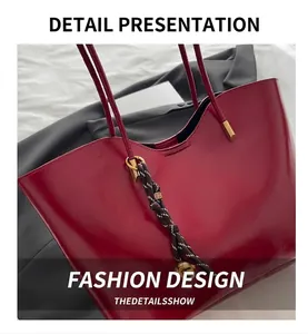Detail of red wax leather tote bag with braided charm on white fabric backdrop