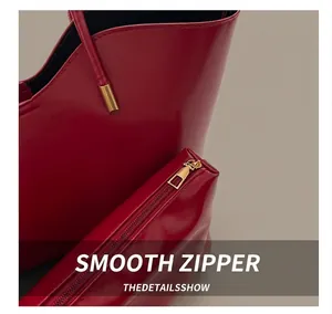 Close-up of a smooth gold metal zipper on a premium red leather tote bag insert