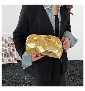 Close-up of golden metallic cloud clutch with pleated texture and magnetic closure