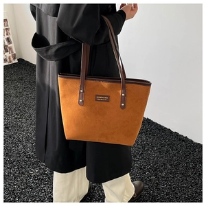Vintage caramel suede tote bag with leather straps on model in black coat