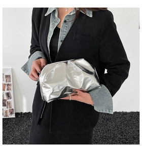 Detail of silver metallic pleated clutch bag held against a minimalist background