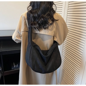 Detailed back view of a large black canvas crossbody crescent bag on a model