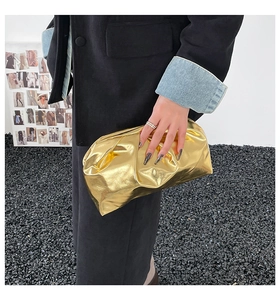 Detail of metallic gold cloud clutch bag with pleated leather texture and kiss-lock closure