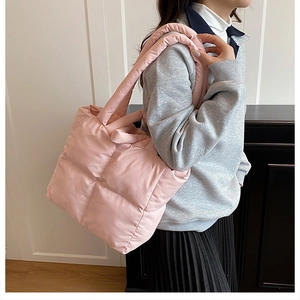 Lifestyle shot of pink quilted puffer tote bag worn on shoulder by a model