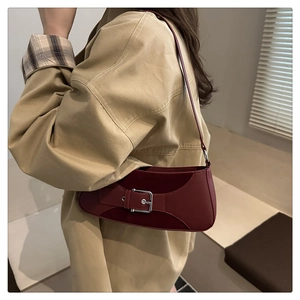 Detail view of burgundy leather underarm bag with silver metallic buckle on model